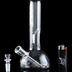 A glass water pipe (bong) with a clear glass bowl and accompanying accessories, reflected on a black surface.