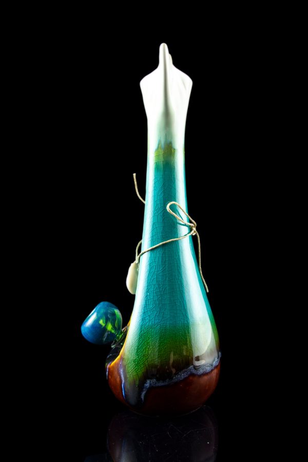 Tall, colorful glass bong with intricate swirls and a small glass marble attached by twine, against a black background.