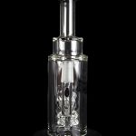 Clear glass oil rig with intricate bubbler design, displayed on a reflective surface against a black background.