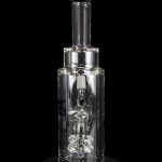 Clear glass dab rig with intricate percolator and vapor pathway, displayed on a reflective surface.