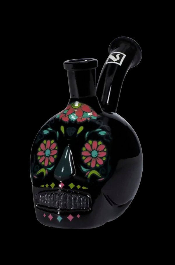 Black glass skull-shaped water pipe with colorful floral Day of the Dead-inspired designs.