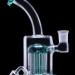 A turquoise glass water pipe (rig) with multiple diffusion stems and accompanying quartz banger and carb cap, isolated on a black background.