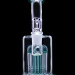 Glass bubbler water pipe with multiple diffusion stems, illuminated in blue against a black background.