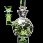 Green glass water pipe (bong) with intricate floral designs, isolated on a black background.