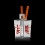 Clear glass dab rig with orange accents and Dutch windmill design, studio shot.