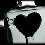 A glass cannabis water pipe shaped like a heart, silhouetted against a pale green background.