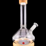 Glass water pipe with a wooden base and a Canadian maple leaf design, isolated on a black background.