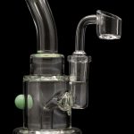 Clear glass dab rig with green accents and a quartz banger.