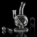 Clear glass water pipe (bubbler) with accompanying glass pieces and lighter, studio shot against a black background.