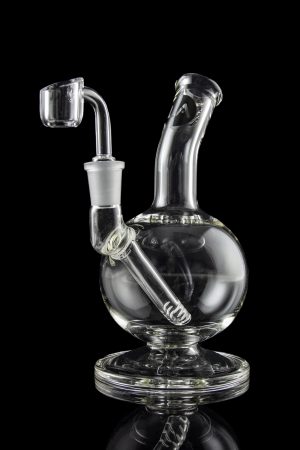 Clear glass dab rig with intricate design and accompanying nail, isolated on a black background.