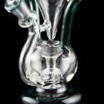 Clear glass water pipe (rig) with intricate bubbler design, isolated on black.