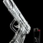 Clear glass pipe shaped like a handgun, displayed with a lighter.