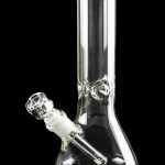 Clear glass bong with a downstem, reflecting on a black surface.