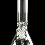 Clear glass bong with intricate detailing, reflecting on a dark surface.