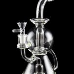 Clear glass water pipe (rig) with intricate bubbler design, isolated on black.