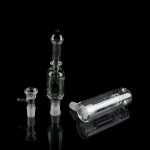 Clear glass cannabis bubbler, oil rig, and bowl displayed on a reflective surface against a black background.