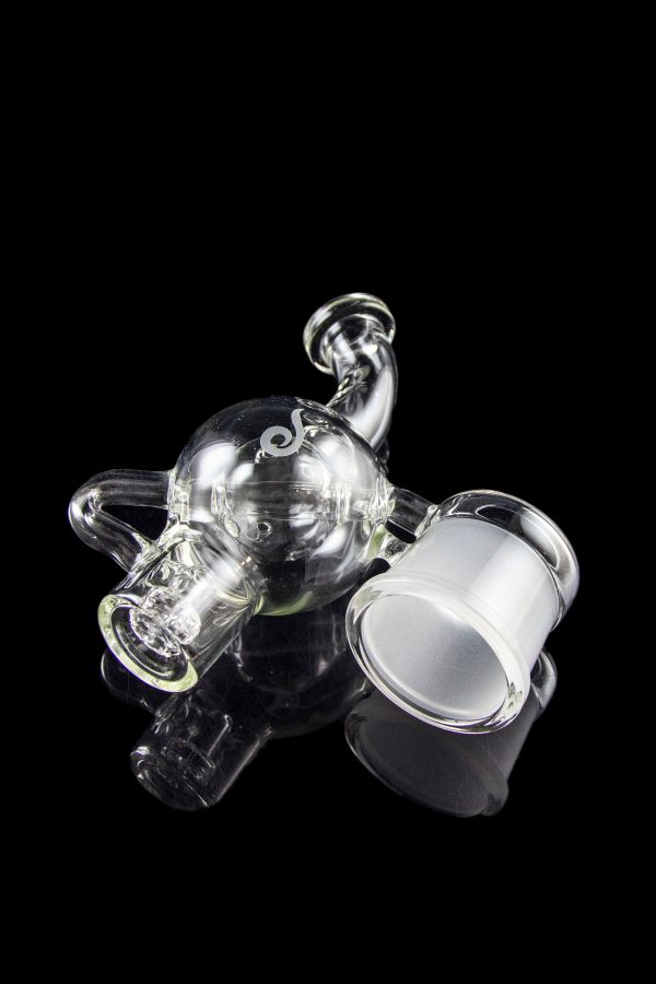 Clear glass rig with intricate bubbler design, isolated on a black background.