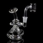 Clear glass dab rig with intricate sculptural design, reflecting on a black surface.