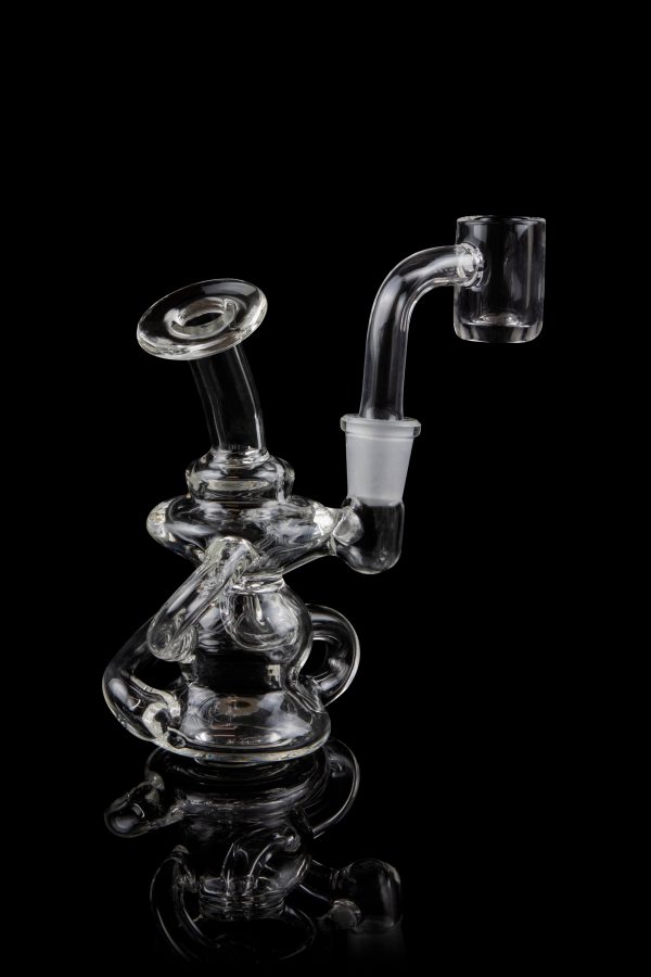 Clear glass dab rig with intricate sculptural design, reflecting on a black surface.
