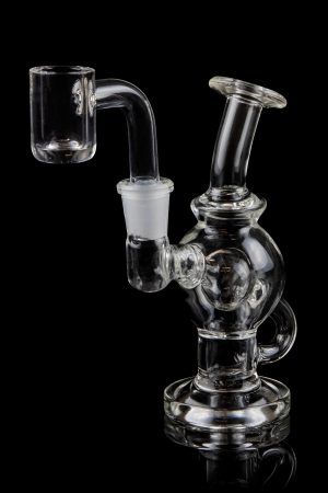 Clear glass dab rig with quartz banger, isolated on black.
