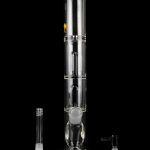Clear glass bong with multiple filtration chambers and accompanying glass pieces, displayed on a reflective surface against a black background.