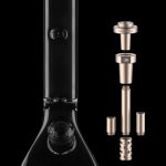 Black glass bong with disassembled gold-toned downstem and accessories on a dark background.