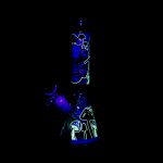 Glowing glass water pipe with psychedelic mushroom and face designs against a black background.