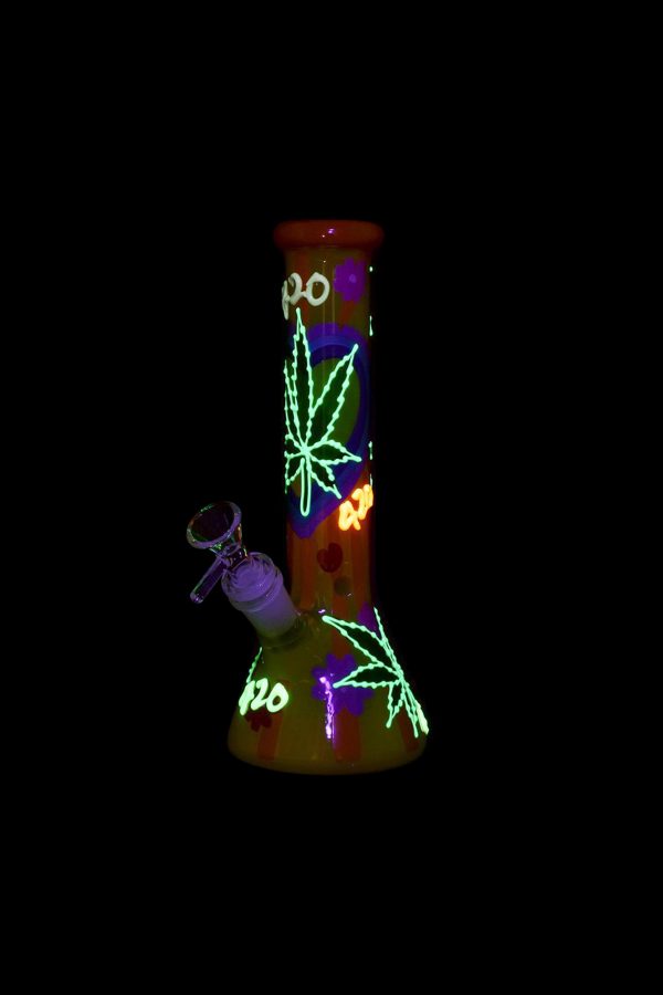A glowing glass water pipe decorated with cannabis leaves and “420” text, alongside a metal dab tool.