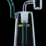 Clear glass dab rig with a bent neck and quartz banger, illuminated with green light.