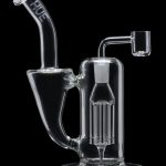 Clear glass dab rig with intricate percolator and quartz nail, isolated on a black background.