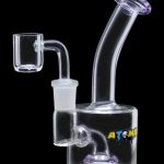 A studio shot of the Atomik Little Dipper Dab Rig, showcasing its compact size and clear glass construction from a three-quarter angle.