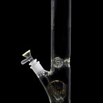 A green-accented glass bong with a clear tube and intricate etched design.