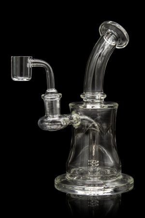 Clear glass dab rig with quartz banger, isolated on a black background.