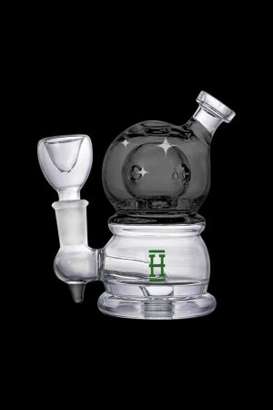 Clear glass rig with a dark grey dome and intricate detailing, featuring a green logo.