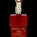 Red glass cannabis oil vial with ornate golden accents and a stylized pagoda design.