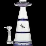 Clear glass water pipe shaped like a UFO with a cowboy riding a bucking bronco silhouetted within the water chamber, against a dark background.