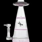 Pink glass water pipe shaped like a UFO with a cow illustration.