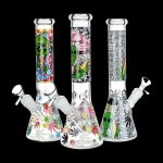 Three decorated glass bongs with cannabis leaf and alien designs against a black background.