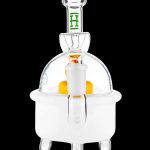 Clear glass dab rig with orange accent and green detailing, isolated on a black background.