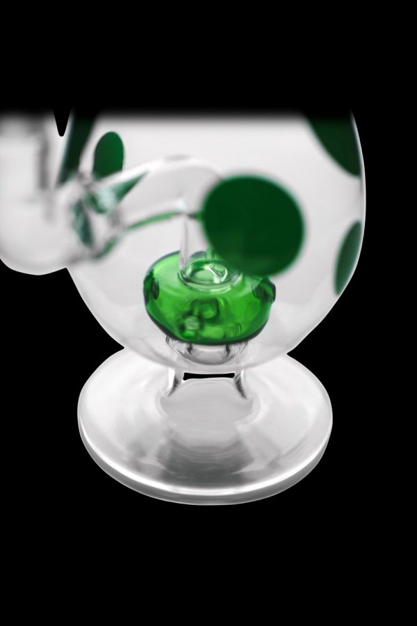 Green and white glass oil rig with a rounded base against a black background.