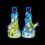 Hand-blown glass water pipe shaped like a whimsical mushroom forest with a smiling face and intricate details, displayed from two angles on a black background.
