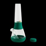 Green silicone bong with a glass downstem and removable lid, isolated on a black background.