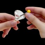 Hands applying cannabis concentrate to a glass dab rig.