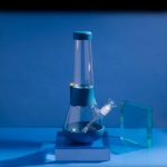 Blue glass bubbler water pipe with a silicone base, studio shot.